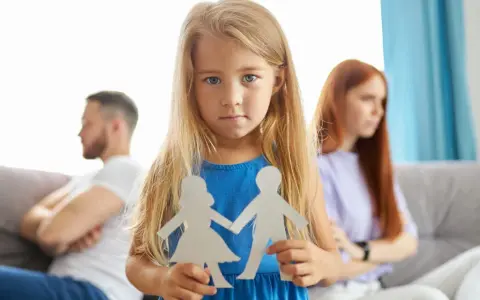 Bambina con sagome di carta di una coppia, mentre i genitori separati sono sullo sfondo.