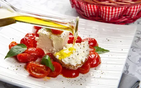 Un piatto di pomodorini confit con robiola, perfetto per una gravidanza sana e gustosa. Olio d'oliva versato su una fetta di pane con formaggio.