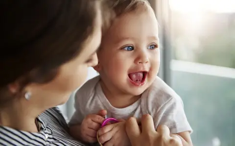 Bambino sorridente con mamma, forse è l'inizio della lallazione.