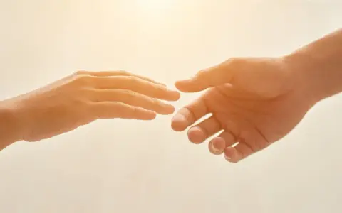 Due mani si tendono l'una verso l'altra, un gesto che può simboleggiare il superamento della differenza tra ansia e paura, trovando conforto.