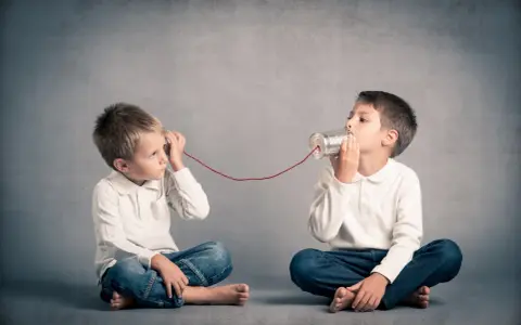 Due bambini comunicano con un telefono di latta. Come mio figlio ha iniziato a parlare a 4 anni, mi immagino che stiano condividendo segreti.