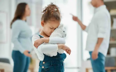 Bambina abbraccia peluche, turbata dalle liti dei genitori separati.