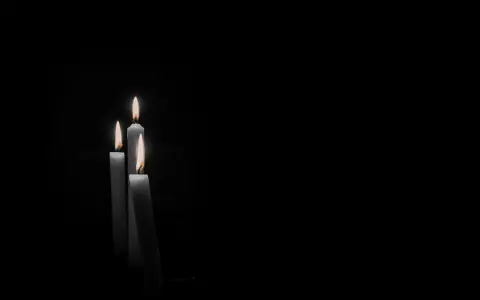 Tre candele accese nel buio, un'immagine che evoca il **stress da lutto sintomi fisici**, come il senso di vuoto e la fragilità.