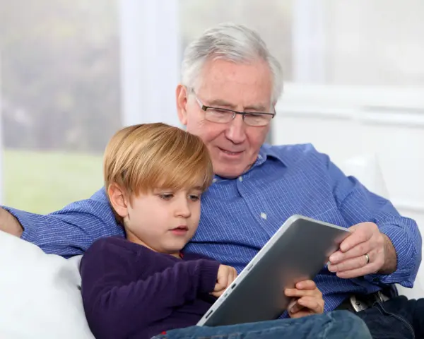 Nonni che non aiutano, ma osservano il nipote giocare sul tablet.