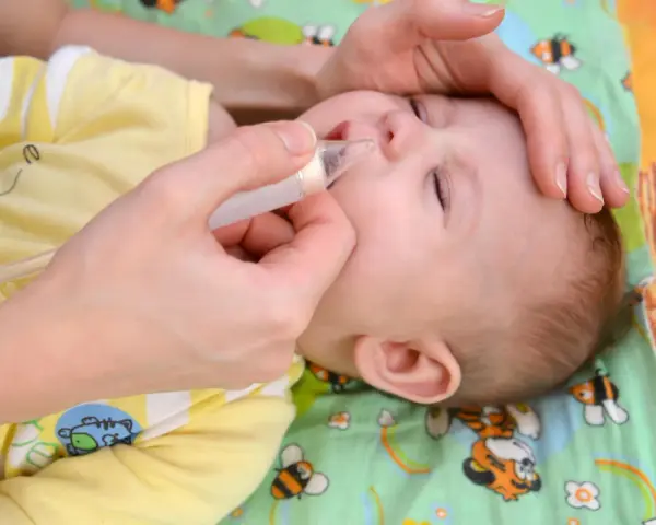 Mani che aiutano un neonato a liberare il naso dal muco, evitando il soffocamento.