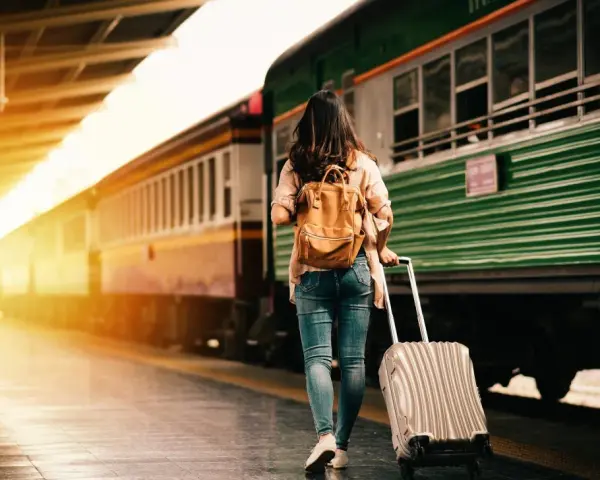 Donna con zaino e trolley in stazione, pronta a cambiare vita a 30 anni.