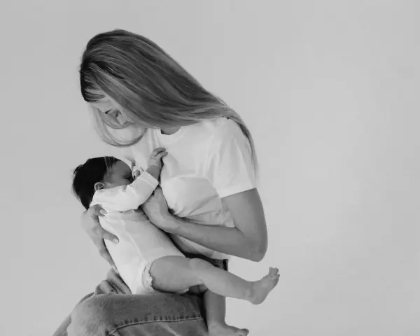 Madre con neonato in braccio, un momento intimo di allattamento. Non c'è traccia di fumare in allattamento, solo amore e cura.