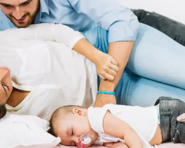 Un neonato dorme sereno tra i genitori. Un momento di pace, un nuovo inizio, quando si ricomincia a vivere dopo un figlio.