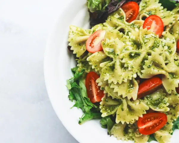 Deliziosa pasta fredda per bambini, con farfalle al pesto e pomodorini freschi, un piatto colorato e gustoso.