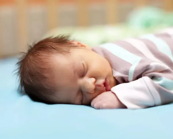 Un neonato dorme sereno, ma chissà se i neonati sognano incubi. La sua manina è vicino alla bocca, il pigiamino a righe lo avvolge.