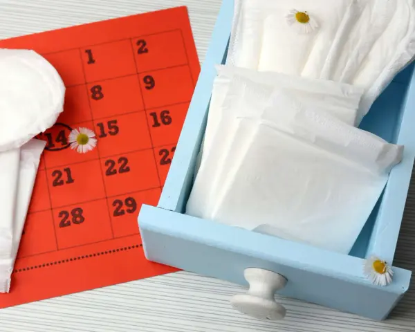 Calendario rosso con cerchiato il 14, assorbenti e fiori di campo. Nessun segno di sangue durante ovulazione incinta.