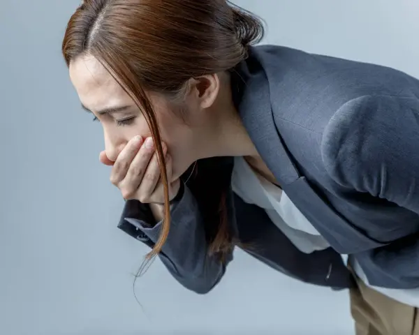 Donna con la mano sulla bocca, visibilmente sofferente, con la paura di vomitare.
