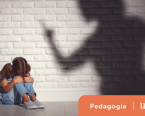 Bambina spaventata seduta a terra, ombra minacciosa di un adulto. Un'immagine che evoca le conseguenze delle punizioni corporali sui bambini.