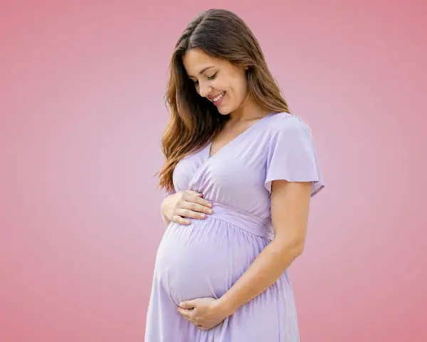 Donna incinta sorride, accarezzando il pancione. Importante assumere acido folico prima o dopo i pasti per la salute del bambino.