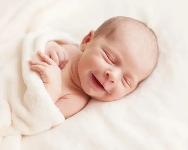 Un adorabile neonato non dorme, ma sorride beatamente avvolto in una coperta morbida.