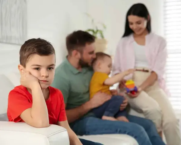 Bambino annoiato, forse per la nascita del fratellino e le conseguenti crisi isteriche. La famiglia è sullo sfondo.