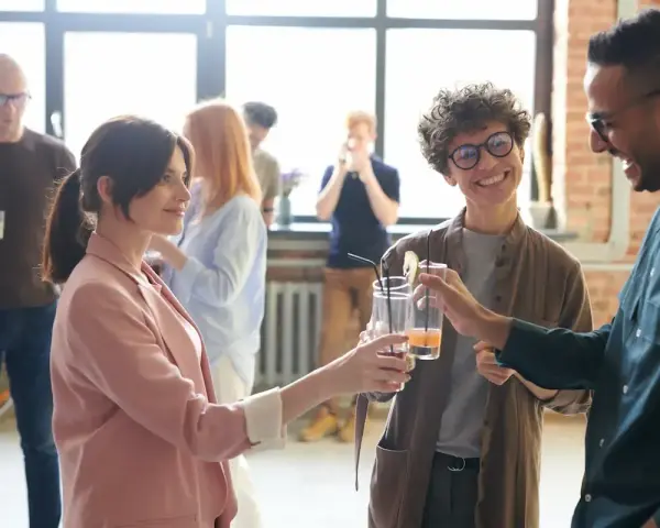 Persone brindano con drink, i loro occhi che si incrociano trasmettono un'ansia sottile, ma anche speranza.