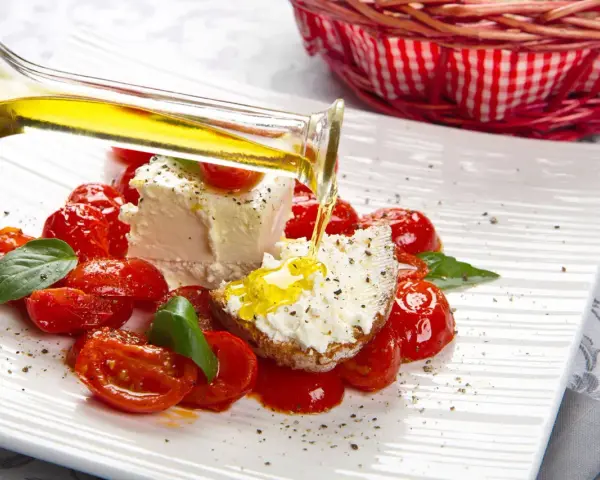 Un piatto di pomodorini confit con robiola, perfetto per una gravidanza sana e gustosa. Olio d'oliva versato su una fetta di pane con formaggio.
