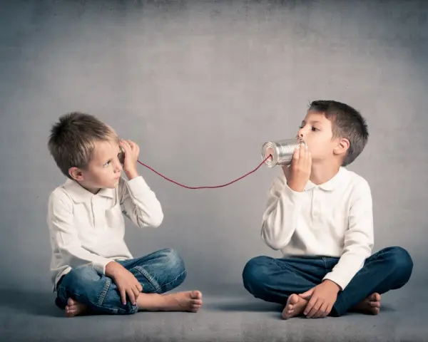 Due bambini comunicano con un telefono di latta. Come mio figlio ha iniziato a parlare a 4 anni, mi immagino che stiano condividendo segreti.