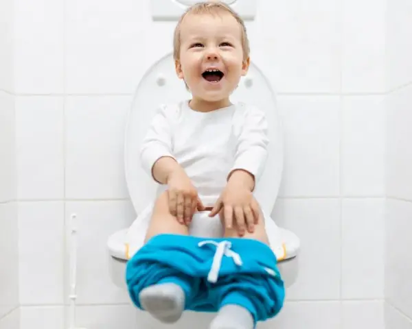 Bambino felice sul water, pantaloni abbassati, pronto per fare la cacca.