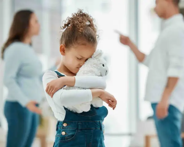 Bambina abbraccia peluche, turbata dalle liti dei genitori separati.