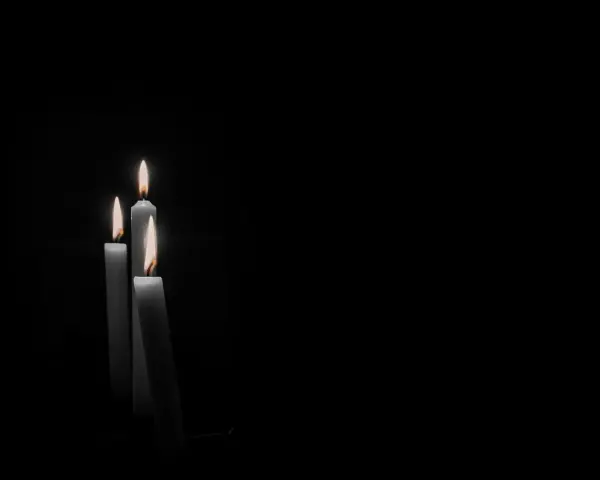 Tre candele accese nel buio, un'immagine che evoca il **stress da lutto sintomi fisici**, come il senso di vuoto e la fragilità.