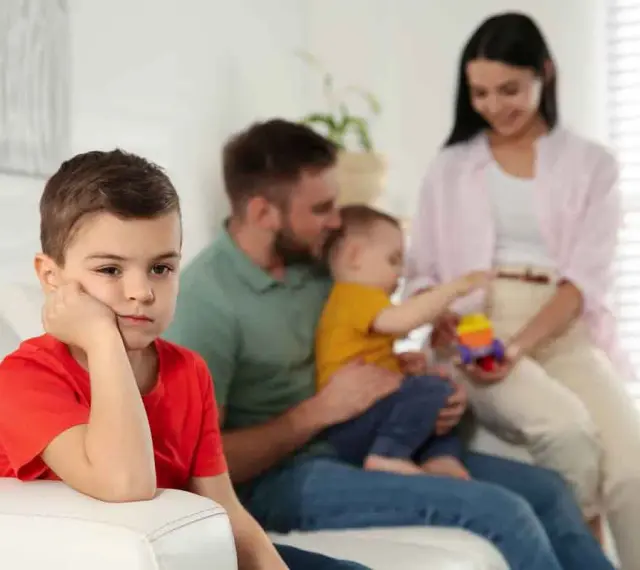 Bambino annoiato, forse per la nascita del fratellino e le conseguenti crisi isteriche. La famiglia è sullo sfondo.