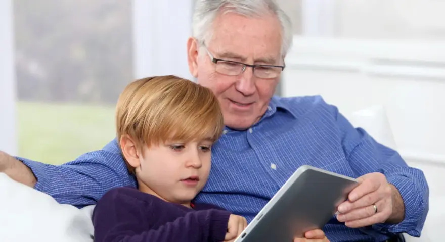 Nonni che non aiutano, ma osservano il nipote giocare sul tablet.
