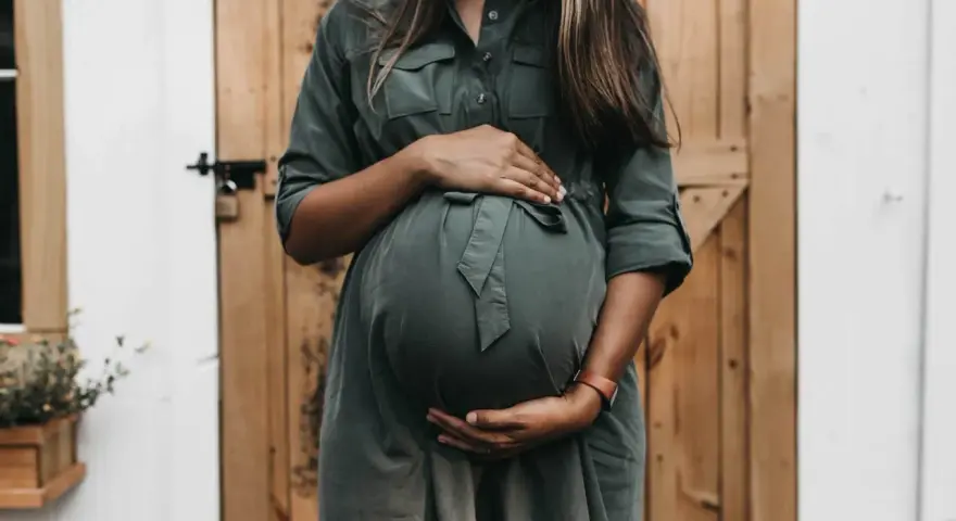 Donna incinta con mani sul pancione, in attesa di un bambino. Un momento di gioia che spesso include l'analisi sangue gravidanza.
