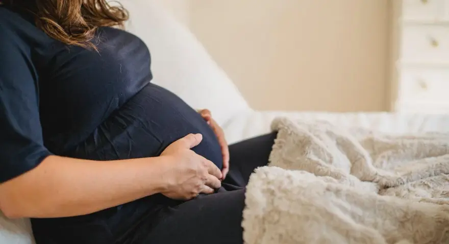 Donna incinta accarezza il pancione, preoccupata per la possibile escherichia coli in gravidanza.