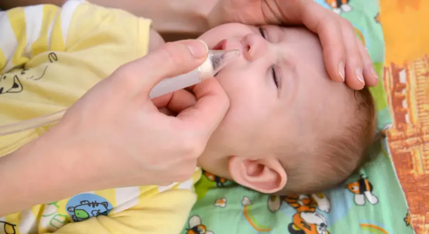 Mani che aiutano un neonato a liberare il naso dal muco, evitando il soffocamento.