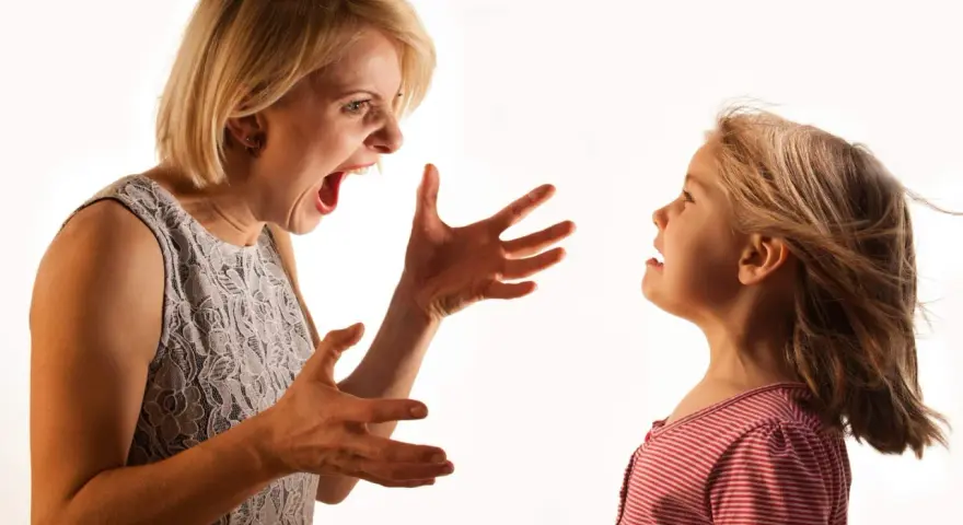 Una madre sgrida il figlio con veemenza, le mani aperte in un gesto di rimprovero. La bambina la guarda, visibilmente scossa.