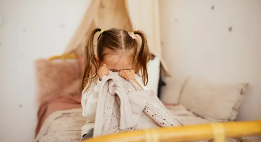 Bambina di 5 anni si nasconde nel plaid, forse per le paure notturne.