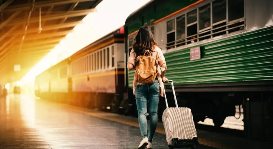 Donna con zaino e trolley in stazione, pronta a cambiare vita a 30 anni.