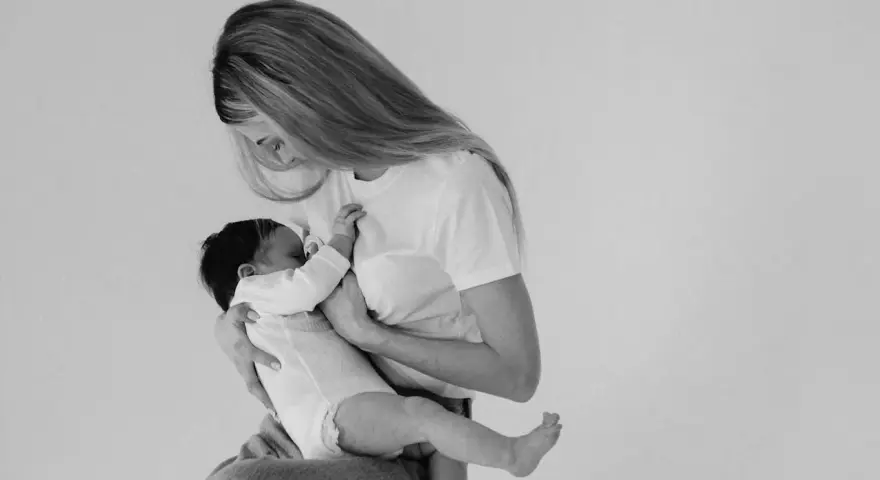 Madre con neonato in braccio, un momento intimo di allattamento. Non c'è traccia di fumare in allattamento, solo amore e cura.