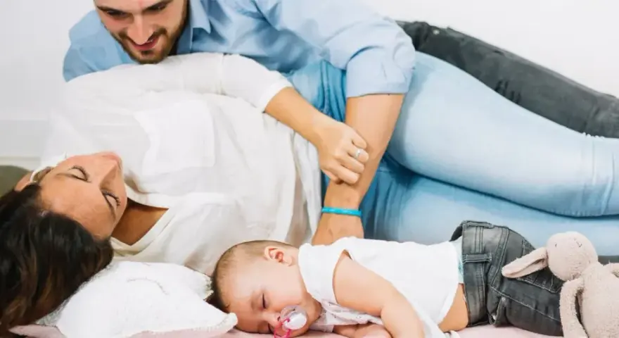 Un neonato dorme sereno tra i genitori. Un momento di pace, un nuovo inizio, quando si ricomincia a vivere dopo un figlio.