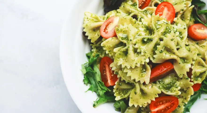 Deliziosa pasta fredda per bambini, con farfalle al pesto e pomodorini freschi, un piatto colorato e gustoso.