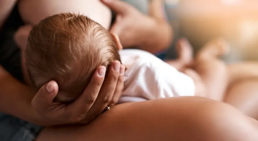 Un neonato si nutre al seno, la sua testolina è tenuta da una mano. La montata lattea non arriva, ma l'amore è presente.