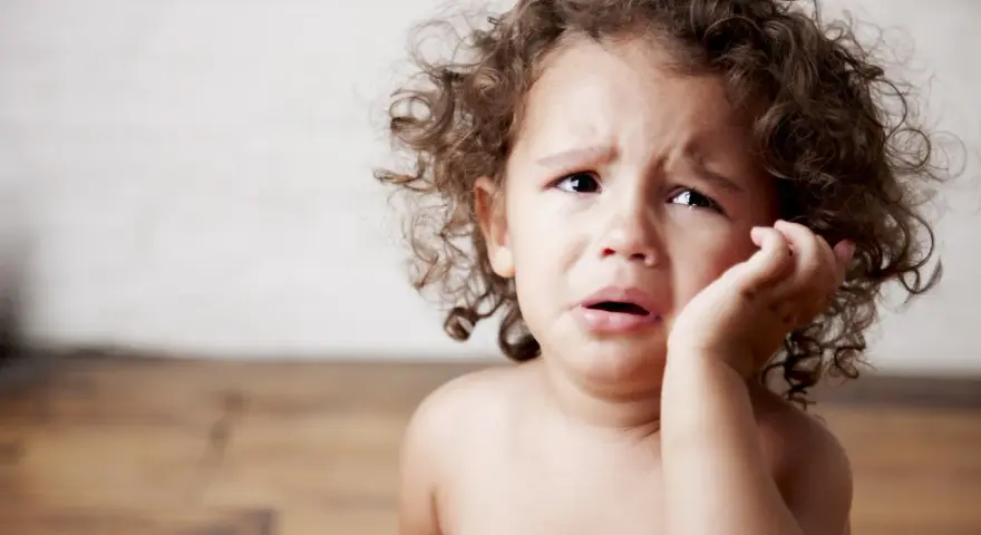 Bambino con riccioli castani piange, forse è un modo per comunicare il disagio, ecco perchè i bambini mordono.