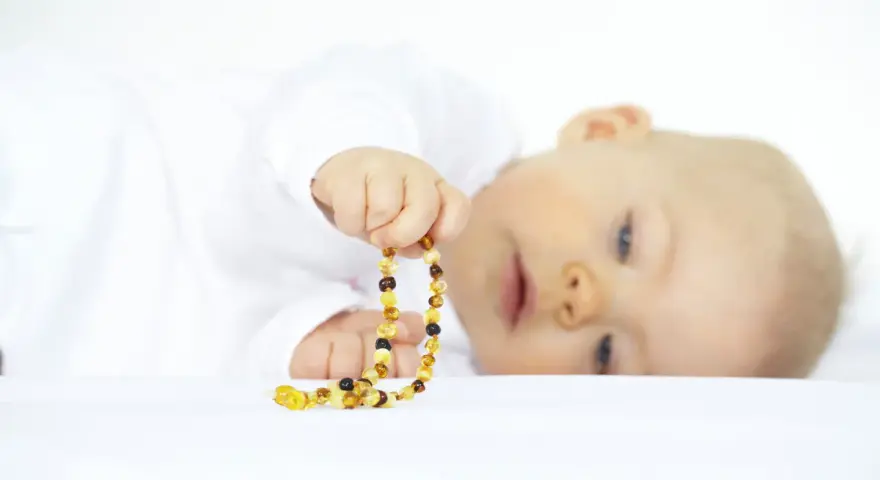 Bambino con collana ambra neonati pericolosa. Attenzione ai rischi di soffocamento e strangolamento.
