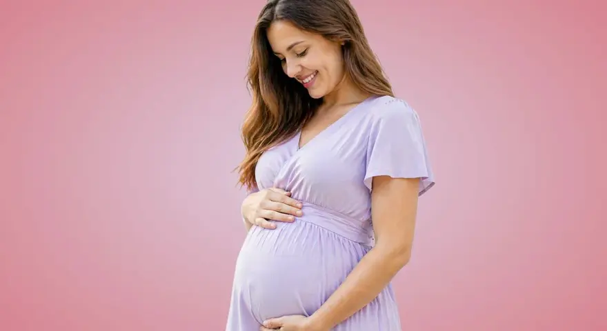 Donna incinta sorride, accarezzando il pancione. Importante assumere acido folico prima o dopo i pasti per la salute del bambino.