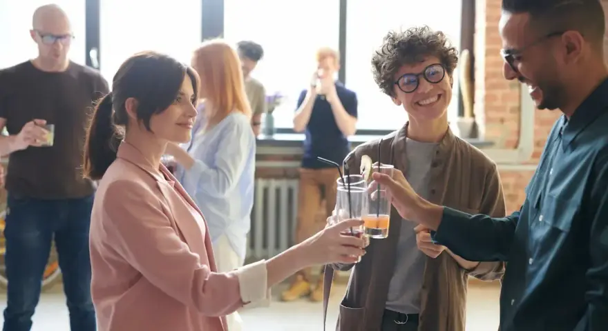 Persone brindano con drink, i loro occhi che si incrociano trasmettono un'ansia sottile, ma anche speranza.