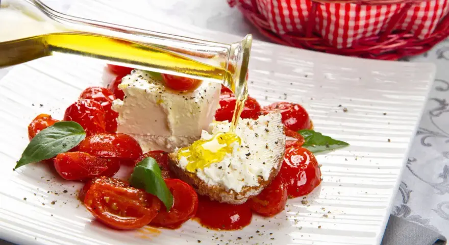 Un piatto di pomodorini confit con robiola, perfetto per una gravidanza sana e gustosa. Olio d'oliva versato su una fetta di pane con formaggio.