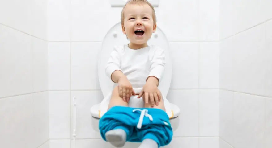 Bambino felice sul water, pantaloni abbassati, pronto per fare la cacca.