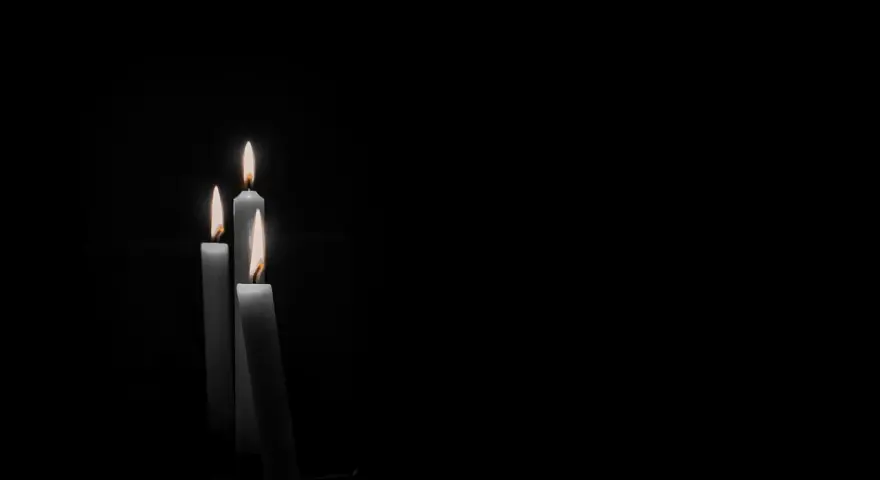 Tre candele accese nel buio, un'immagine che evoca il **stress da lutto sintomi fisici**, come il senso di vuoto e la fragilità.