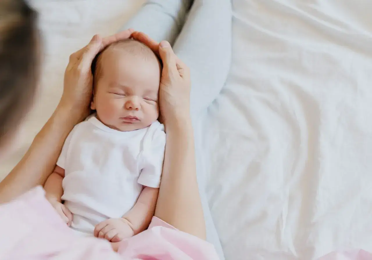 Un neonato dorme sereno, il suo respiro rumoroso è un suono dolce. Mani amorevoli lo cullano.