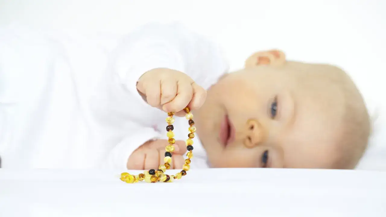 Bambino con collana ambra neonati pericolosa. Attenzione ai rischi di soffocamento e strangolamento.
