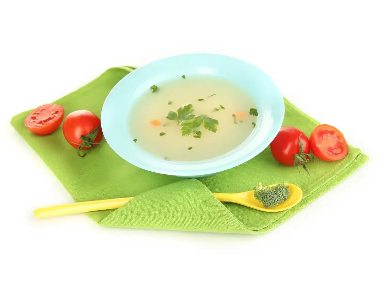 Brodo vegetale svezzamento: un piatto leggero con verdure fresche, pomodorini e un cucchiaino di broccoli, perfetto per i più piccoli.
