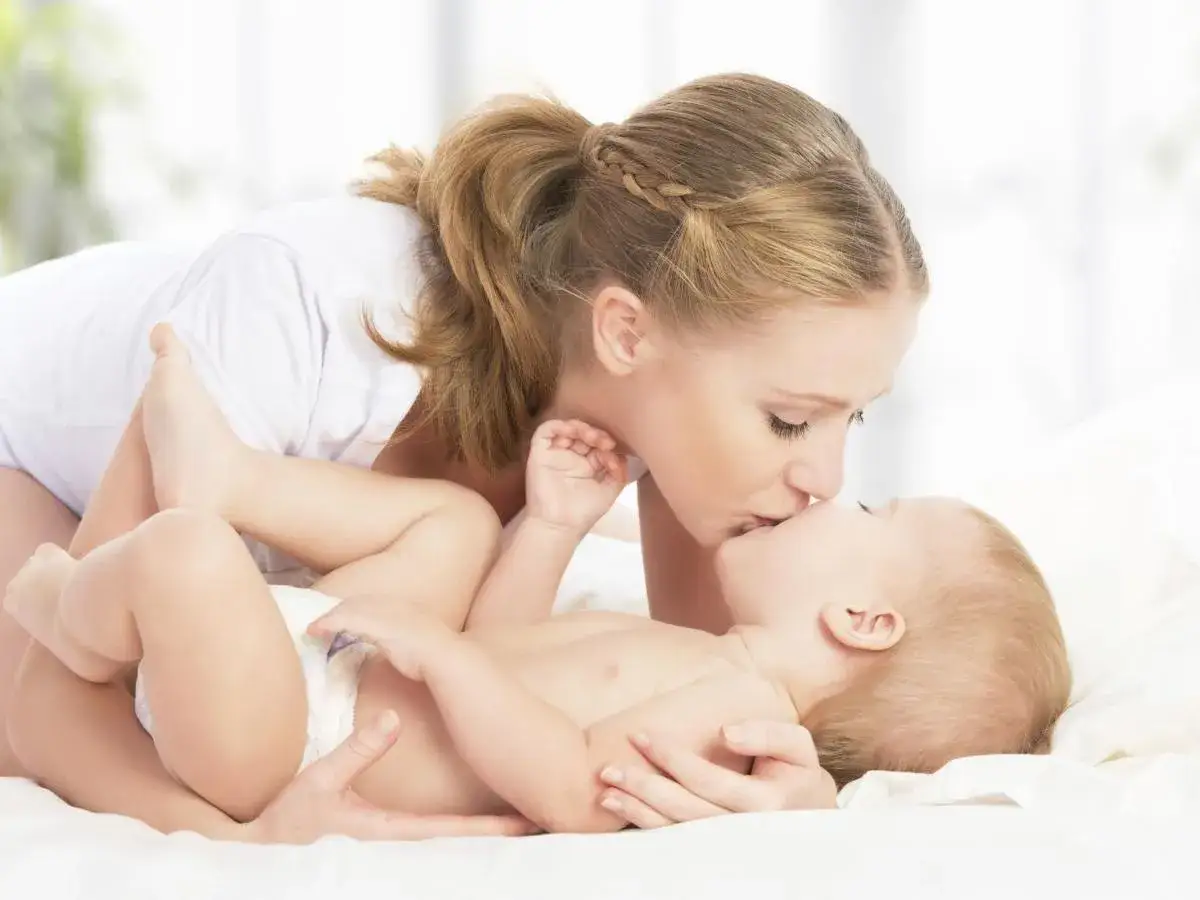 Dolce momento tra mamma e neonato. La mamma bacia il suo piccolo, forse per svegliare neonato per mangiare, con tenerezza.