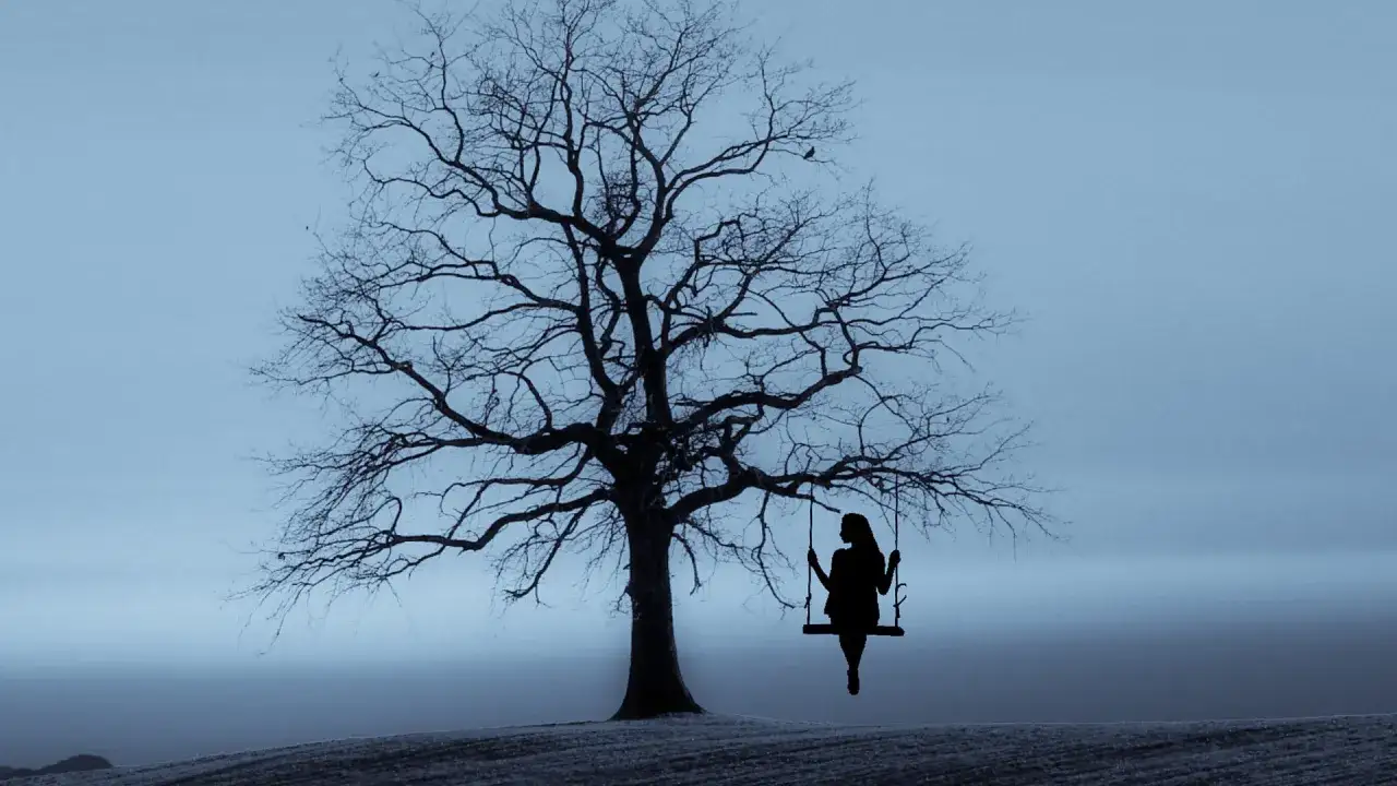 Silhouette di una donna su un'altalena sotto un albero spoglio. Un'immagine che evoca il difficile percorso per perdonarsi dopo un aborto, trovando pace nel silenzio.